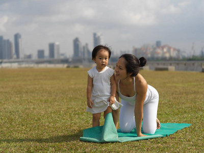 亚洲华人妇女在户外练习瑜伽与年轻女婴