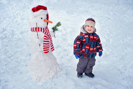快乐美丽的孩子在花园，冬天的时候建设雪人