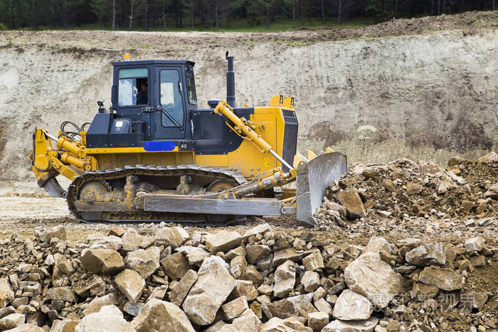 推土机将泥土和碎石铺在公路的堤岸上.