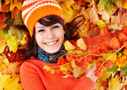 秋天橙色叶子的年轻女人。