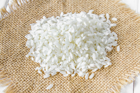 在白色的木板桌上的生白米的谷物。烹调配料