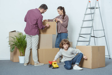 父母包装盒和儿子玩玩具车在搬迁期间