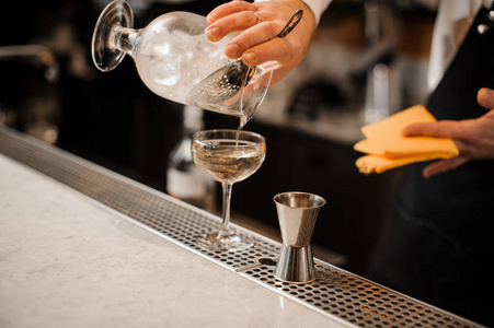 酒保把酒精饮料和冰块混合在一起倒入玻璃杯