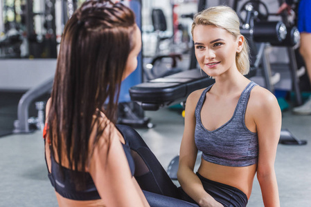 年轻的体育妇女在健身房互相交谈