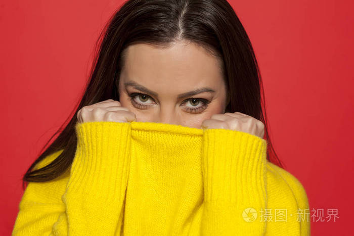 在红色背景的黄色毛衣美丽的羞愧的妇女
