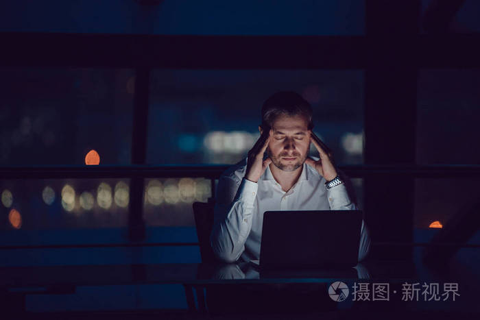 在夜间办公室工作的商人在膝上型电脑