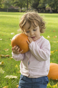 可爱的小女孩拥抱南瓜在秋日的田野上