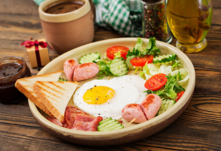 情人节的早餐一颗心形的煎蛋, 土司, 香肠, 培根和新鲜蔬菜。英语早餐