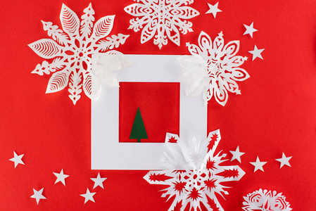 圣诞树在白色框架与星和纸雪花周围, 隔绝在红色