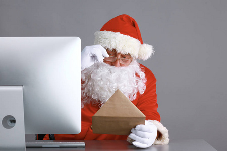 圣诞老人阅读儿童的信件和书面答复他们使用笔记本电脑