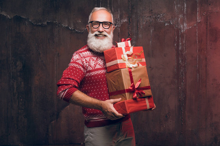 英俊的高级大胡子男子手持礼品盒在黑暗的背景和看着相机。圣诞老人祝圣诞快乐, 新年愉快