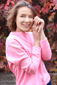 美丽的微笑的女人在粉红色的运动衫户外