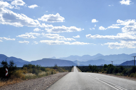 与山在地平线上在晴朗的蓝天底下,与地平线上的山脉下的公路照片
