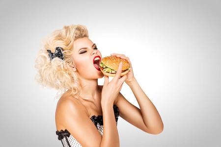 吃汉堡美丽的海报模型在灰色背景下吃汉堡包