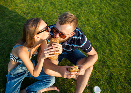 情侣坐在草地上的公园和吃 sandw