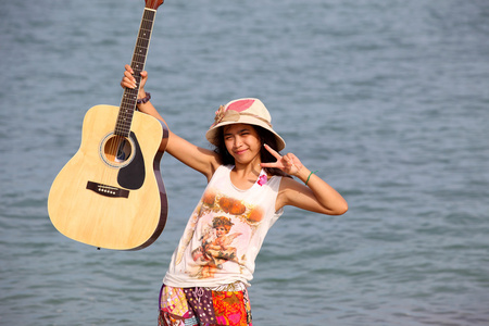 吉他在海滩上的年轻漂亮女人