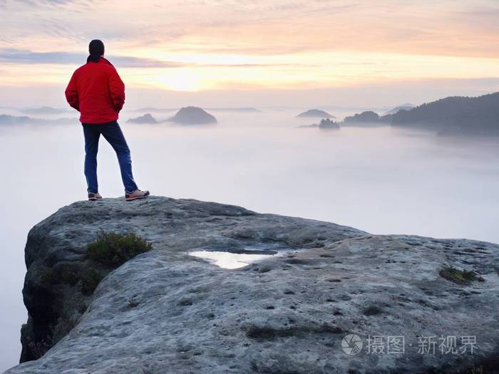 男子徒步旅行者在山的顶峰.在朦胧的秋景的奇妙破晓.太阳藏在云朵