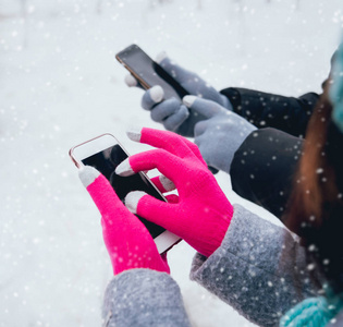 夫妇使用智能手机与手套在冬季触摸屏