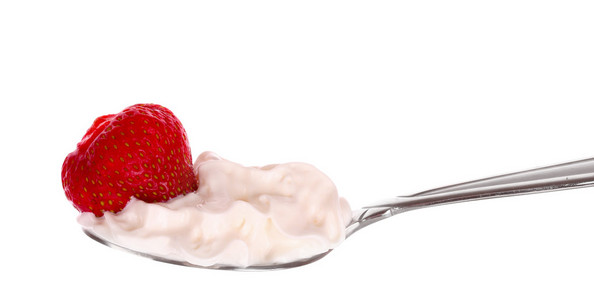 草莓放在勺子里，奶油放在白色