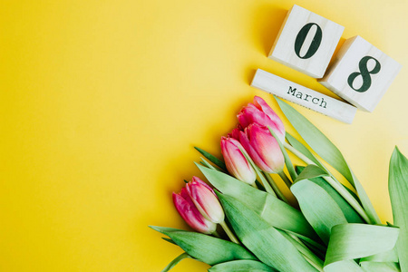 3月8日幸福妇女节的概念。用木制方块日历和粉红色的郁金香在黄色背景。复制空间