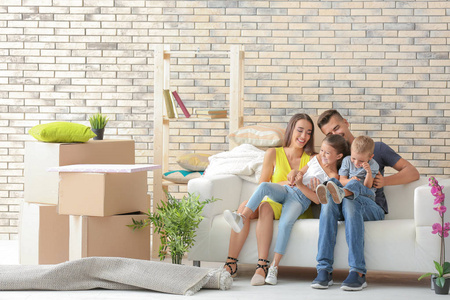 丢沙包男孩快乐的家庭坐在沙发上的房间在新家照片