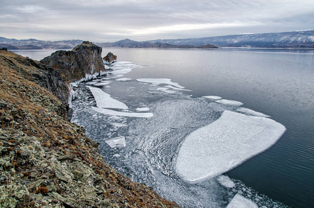 贝加尔湖和岩石在12月的寒冷。冰冻的时间。冰浮冰在水上游泳
