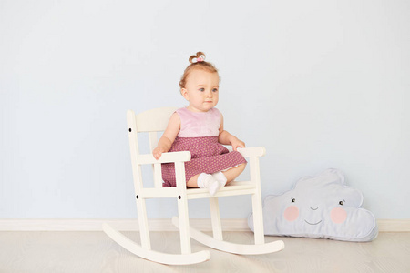 穿着礼服的漂亮小女孩坐在白色的椅子上