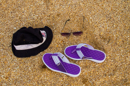 沙滩沙滩上的一双拖鞋帽子和太阳镜