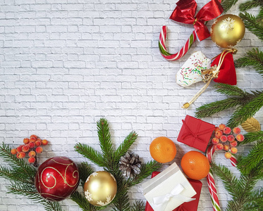 圣诞节组成。圣诞礼物，松果，姜饼，冷杉的枝条与糖果，棒棒糖砖白色背景上。平 顶视图。橘子 饼干 房子