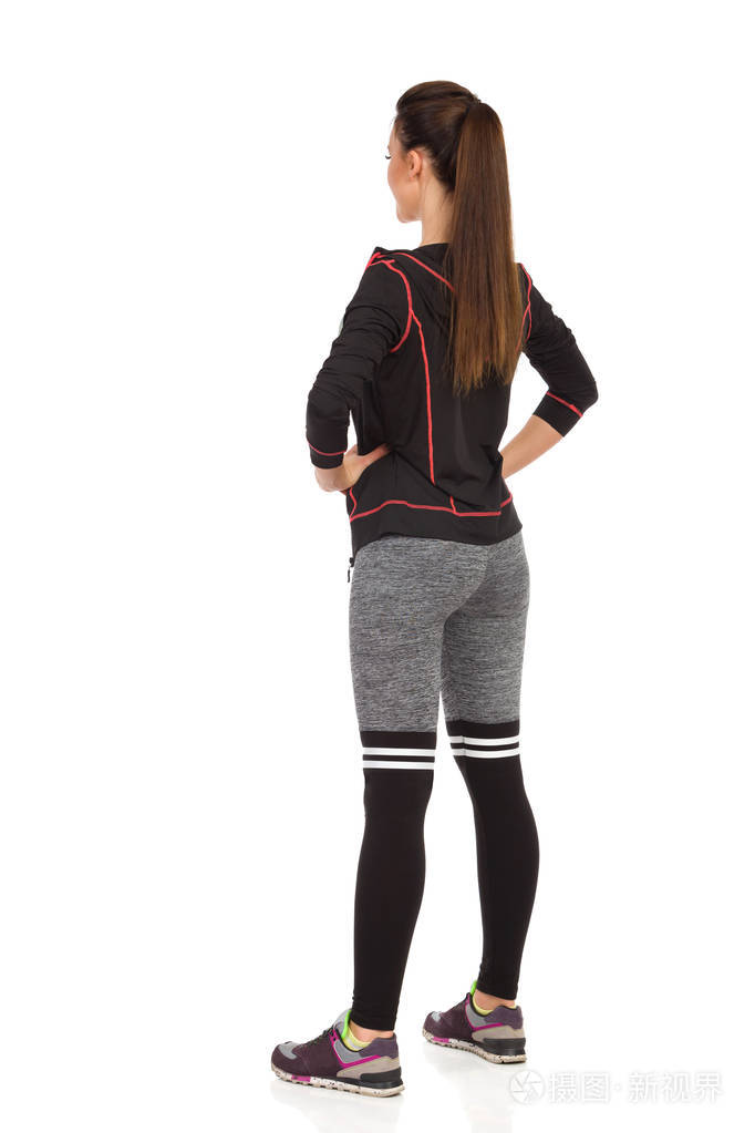 年轻女子在健身服上站立腿分开.后侧视图