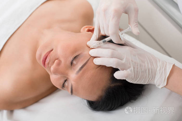 快乐成熟的女人在水疗中心打针