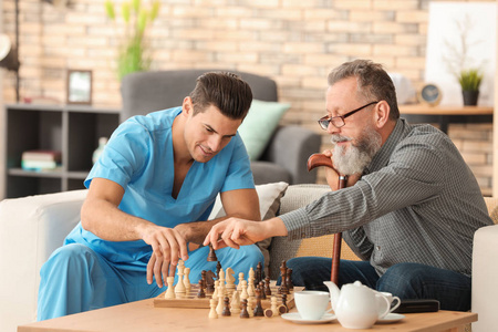 年轻的看护者和老人在家里下棋