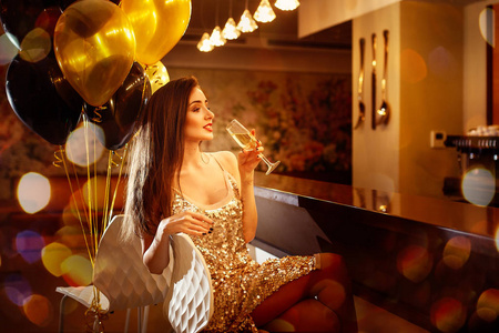 迷人美丽的微笑的女人与香槟和金色气球的背景在餐馆 selebrating 新年, 圣诞节, x mas