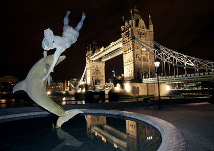 伦敦夜间的海豚雕像和塔桥。