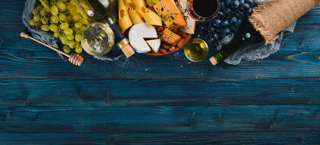 在一张蓝色的木桌上的奶酪葡萄酒蜂蜜坚果和香料的大品种。顶部视图。文本的可用空间