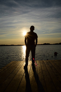 日落前湖面上的年轻男子剪影