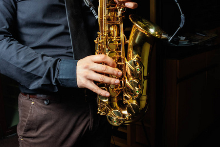 萨克斯球员手萨克斯管吹奏者演奏爵士乐音乐.低音萨克斯乐器特写照片