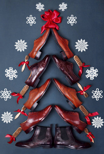 由经典抛光牛津革鞋在蓝色的皮革背景下的圣诞树。创意圣诞树。圣诞销售。圣诞鞋店顶部视图。雪片上的 bacground