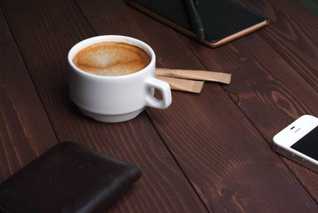 智能手机与笔记本和杯浓咖啡木背景