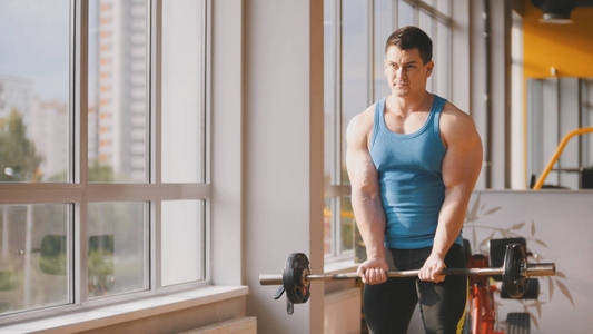 在健身房，训练他的二头肌镜子附近的肌肉男健美