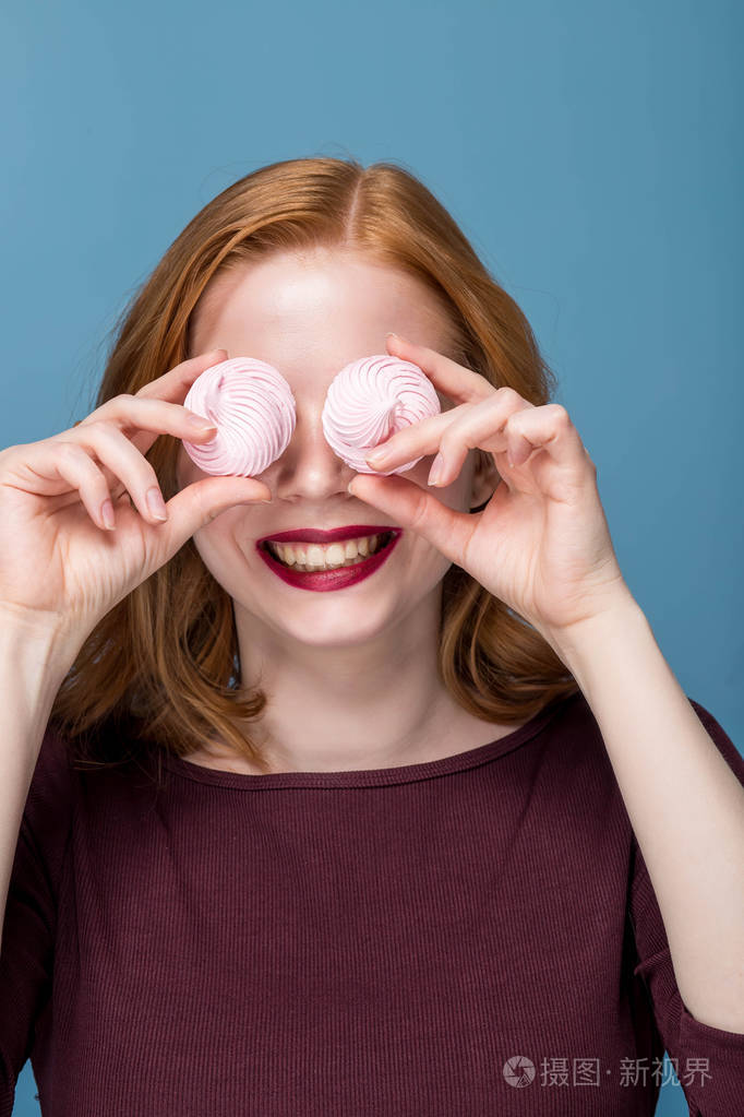 红头发的女孩用棉花糖遮住眼睛.微笑, 积极的情绪, 乐趣, 亲密的肖像