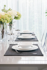 瓷器和玻璃器皿上餐桌与白色和绿色的花朵，在表的中心设置