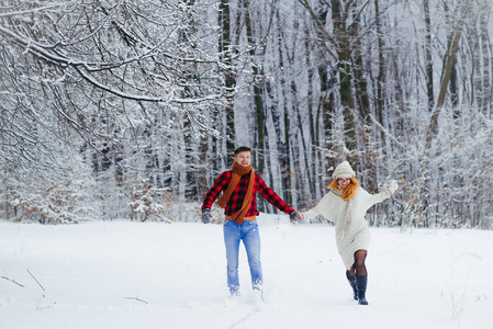 欢快的运行夫妇在雪地上覆盖着积雪的森林