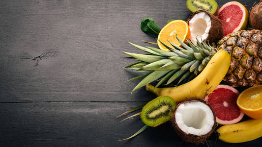 新鲜的热带水果。菠萝, 椰子, 猕猴桃, 橙, 石榴, 葡萄柚。在木制背景上。顶部视图。文本的可用空间