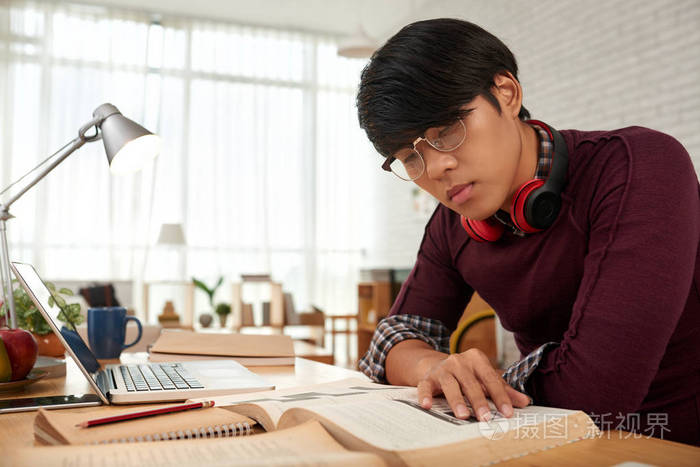 戴眼镜的聪明年轻人的肖像读书学习新事物