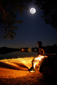 孤独的男人坐在车前看着月亮说话
