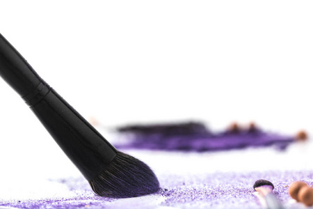 化妆刷在白色表面上拾起紫色的化妆品眼影