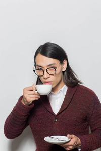 亚洲年轻人喝热茶或咖啡从白色杯子