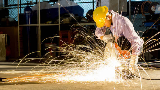 工人使用磨削切割金属, 重点在闪光灯线的尖锐火花, 在低光