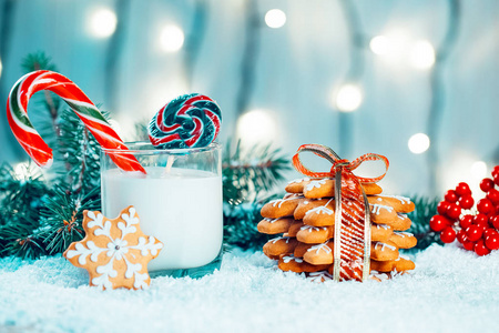 圣诞姜饼和牛奶配上装饰品, 雪, 圣诞树树枝上散模糊的灯光背景。自由空间
